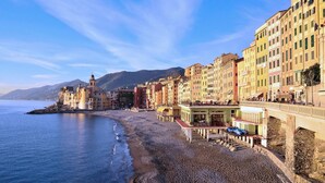 Une ville côtière aux bâtiments aux couleurs vives, avec une plage et une église dotée d’un clocher.