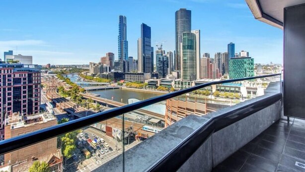 A high-rise building with a view of a city skyline, including several tall buildings and a river. - Riverview Suites by EdgeTrip (Melbourne)