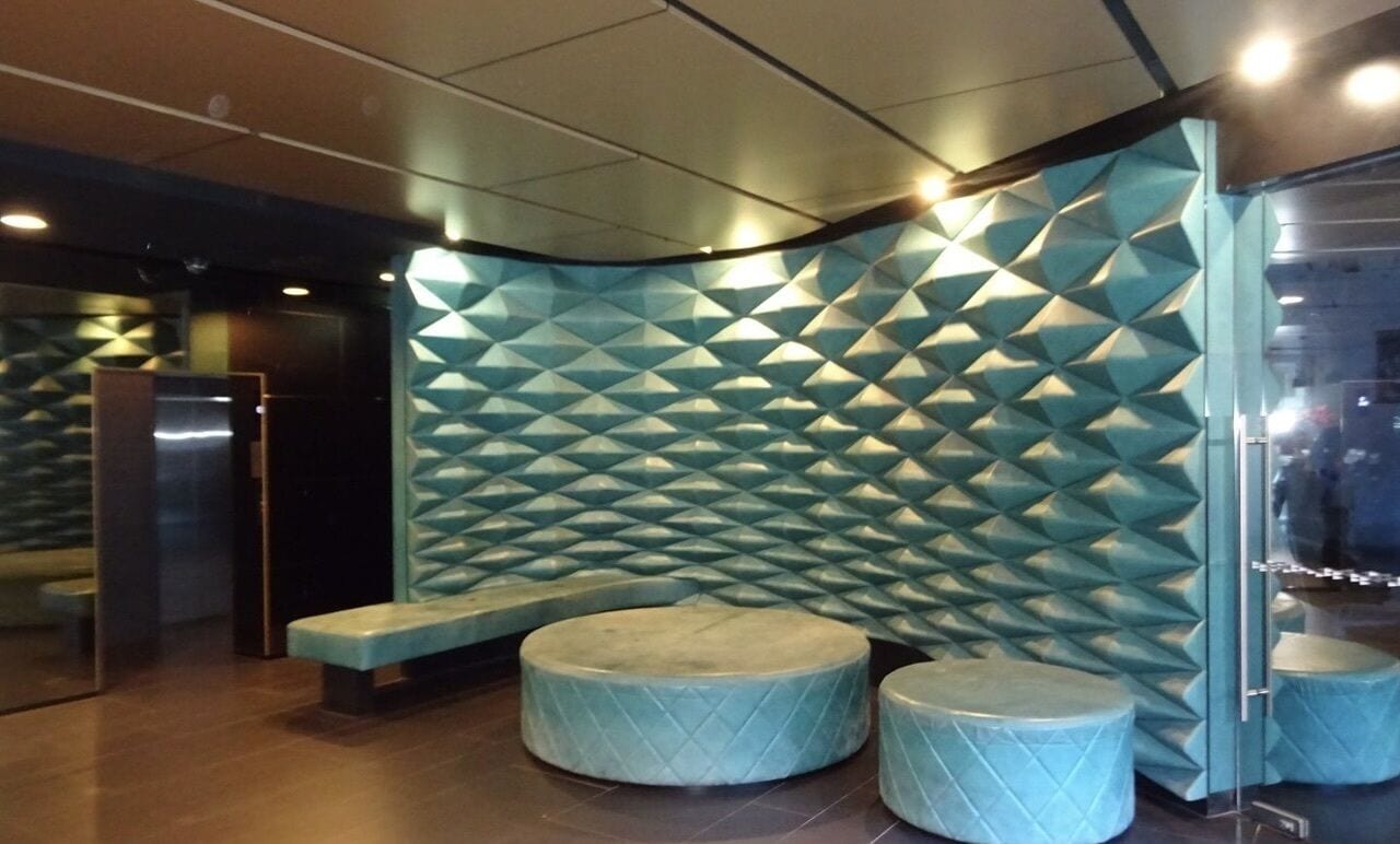 Eine Lobby mit Wand in geometrischem Muster, einer Bank und zwei Sitzbereichen.