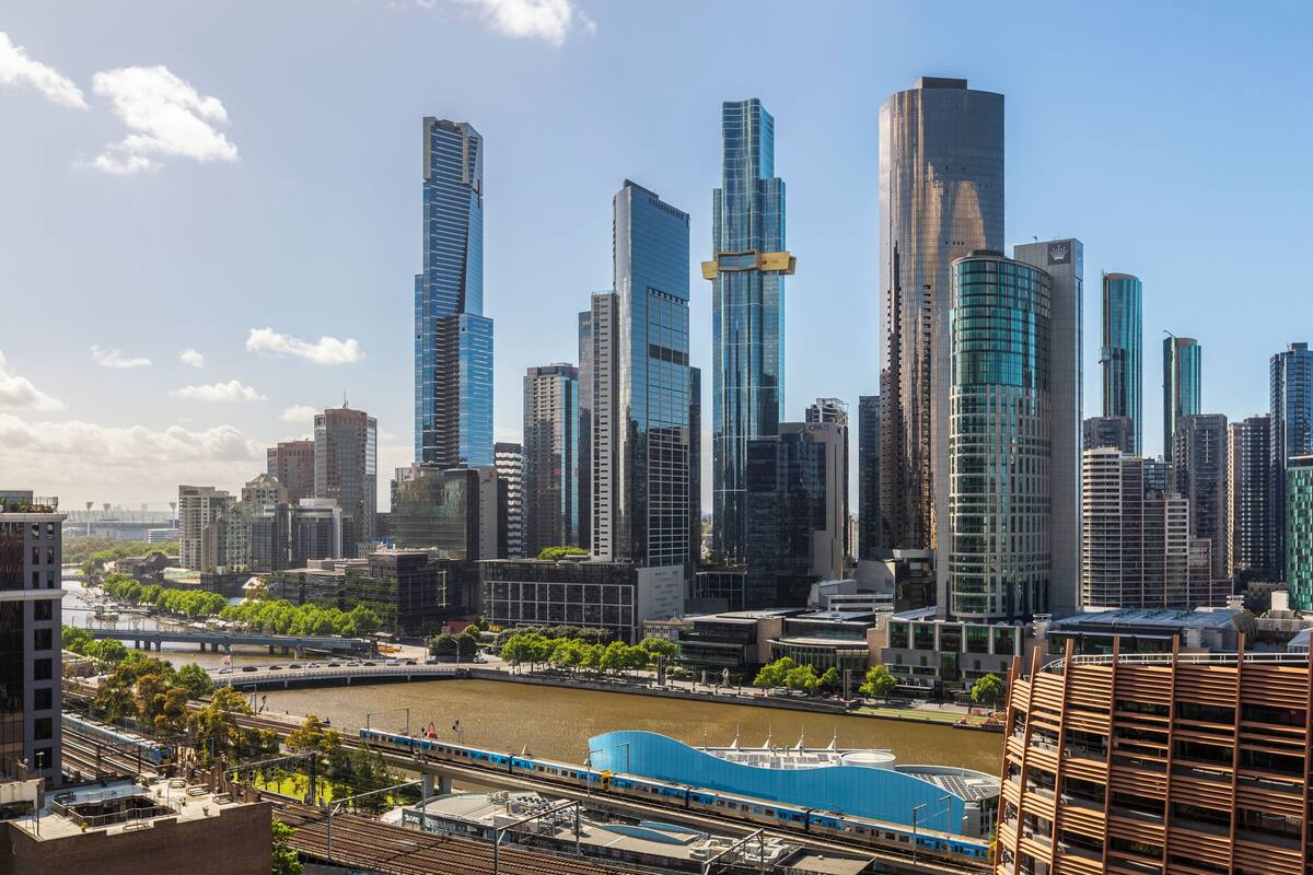 A cityscape with modern skyscrapers, a river, and a train.
