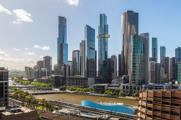 A cityscape with modern skyscrapers, a river, and a train. - Riverview Suites by EdgeTrip (Melbourne)