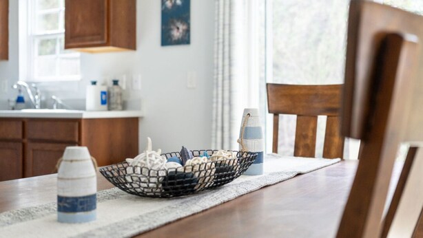 Una mesa de comedor con una cesta tejida que contiene varios objetos, una botella de agua y un candelabro.