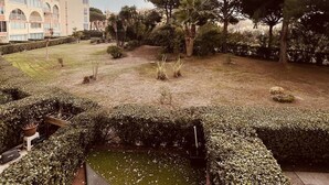 A landscaped courtyard with a small pond, neatly trimmed hedges, and trees. - Nice 2 room with cabin swimming pool Richelieu Cap d'Agde (LE CAP D AGDE)