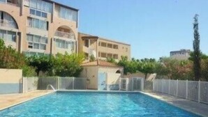 A swimming pool with a clear blue water surface, surrounded by a tiled deck. - Nice 2 room with cabin swimming pool Richelieu Cap d'Agde (LE CAP D AGDE)