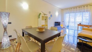 A dining area with a table, chairs, a TV, and a sofa.