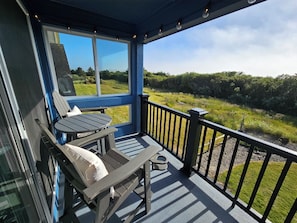 Un espacio de estar al aire libre cubierto, con una mesa y sillas, con vista a un paisaje cubierto de césped.