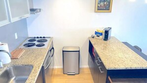 A compact kitchen with a gas stove, a sink, and a trash bin. - Entire apartment 10 min from Clearwater Beach
 (Clearwater)