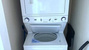 A compact, white washing machine with a front-loading door, a control panel with multiple dials, and a blue detergent dispenser. - Entire apartment 10 min from Clearwater Beach
 (Clearwater)