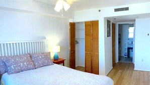 A bedroom with a bed, a nightstand, a lamp, a wardrobe, and a bathroom visible through an open door. - Entire apartment 10 min from Clearwater Beach
 (Clearwater)