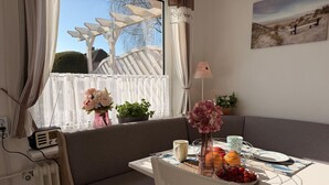 Ein gemütliches Zimmer mit Fenster, einem Tisch mit Obstschale, einem Radio und einer Topfpflanze.
