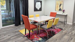 Ein Konferenzraum mit Glastür, einem Tisch, Stühlen und einem farbenfrohen Teppich.