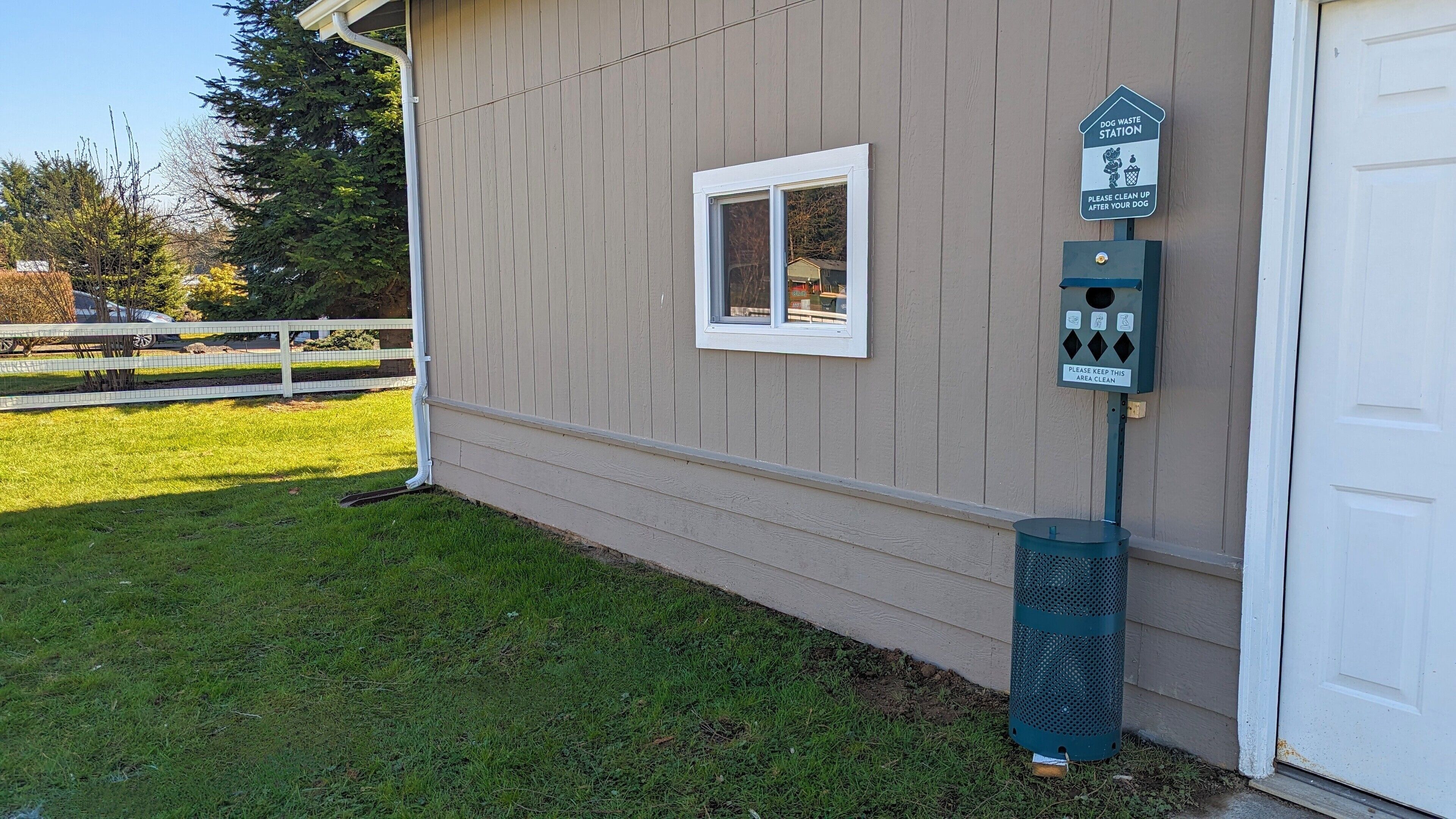 A dog waste station with a sign instructing to clean up after your dog and keep the area clean.