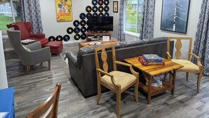 Ein Wohnzimmer mit einer Couch, Sesseln, einem Couchtisch, einem Fernseher und einer Wand voller Schallplatten.