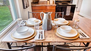 A dining table set with plates, bowls, and glasses, with a pitcher in the center. - Cozy pet-friendly home with fenced backyard, fully equipped for long-term stays. (Louisville)