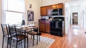 A modern kitchen with wooden cabinets, a black microwave, and a black stove. - Cozy pet-friendly home with fenced backyard, fully equipped for long-term stays. (Louisville)