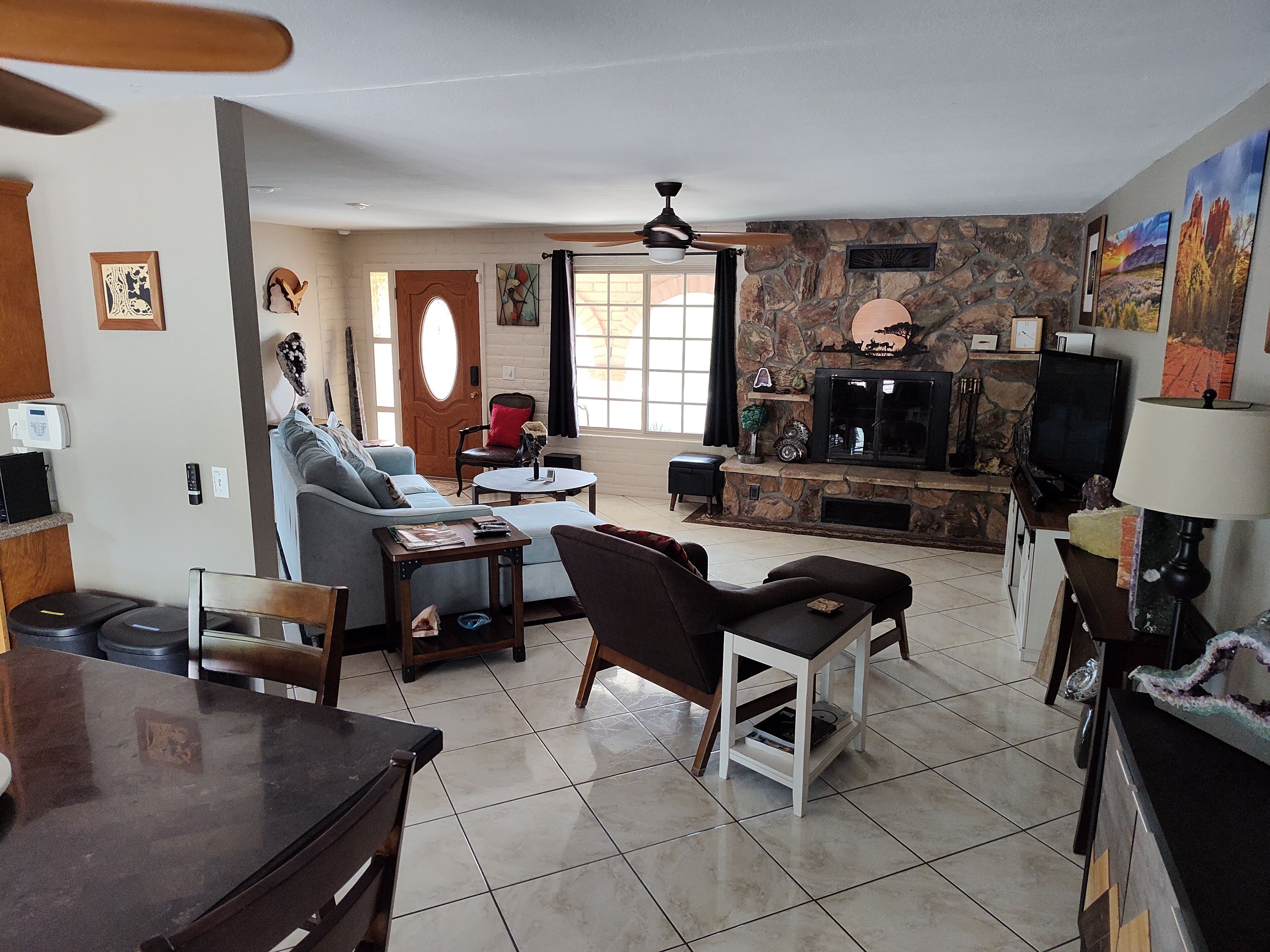 A living room with a stone fireplace, a television, and a dining area with a table and chairs.