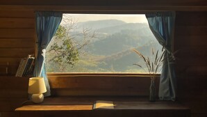 A window with curtains, a lamp, a vase with dried plants, and a book on a wooden ledge. - Midori Coffee Farm (Nam Ban Lam Ha)