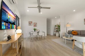 A modern living room with a flat-screen TV, dining area, and seating space.