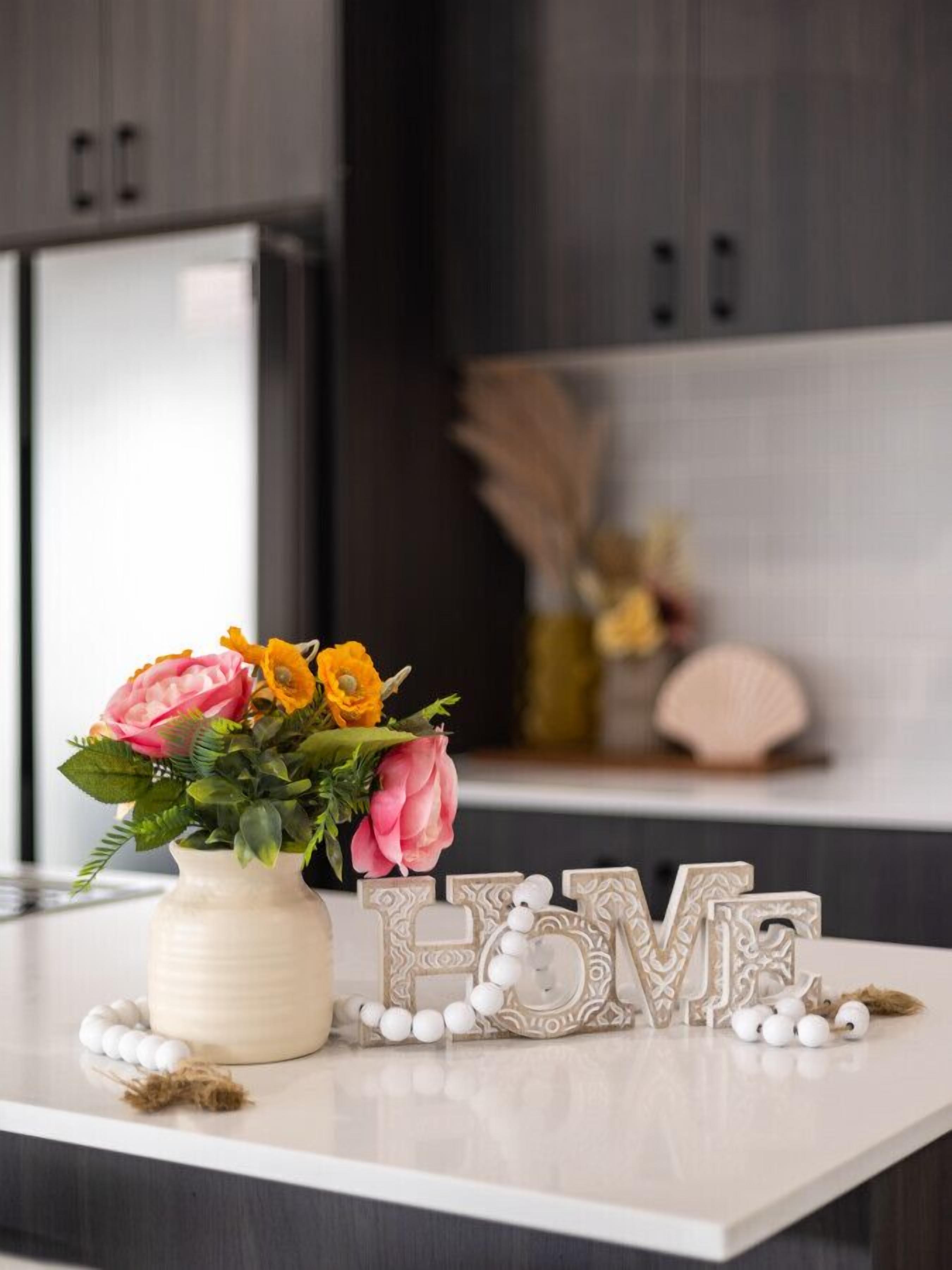 A kitchen counter with a vase of flowers, decorative letters spelling "LOVE", and a shell on the counter.