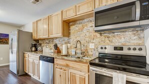 A modern kitchen with wooden cabinets, a stainless steel refrigerator, a built-in microwave, and a dishwasher. - Mountain Retreat (Cascade)
