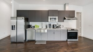 A modern kitchen with stainless steel appliances, grey cabinets, and a wooden floor. - City View 1BR I Gym I Free Parking I Workspace (Dallas)