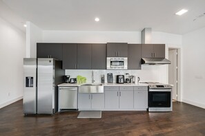 A modern kitchen with stainless steel appliances, grey cabinets, and a wooden floor. - City View 1BR I Gym I Free Parking I Workspace (Dallas)