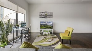 A modern living room with a large window, a dining area, and a yellow armchair. - City View 1BR I Gym I Free Parking I Workspace (Dallas)