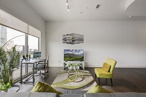 A modern living room with a large window, a dining area, and a yellow armchair. - City View 1BR I Gym I Free Parking I Workspace (Dallas)