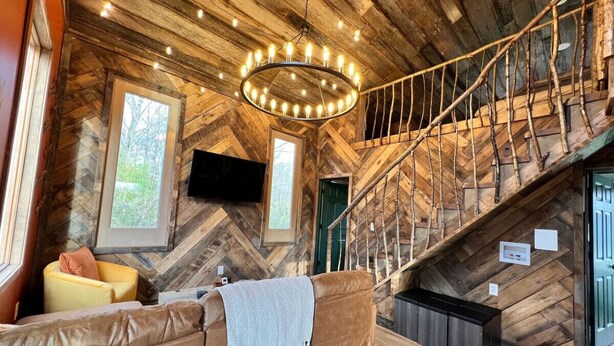 Un interior de madera con una escalera curva, un sofá de cuero y un televisor montado en la pared.