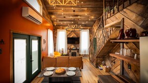 Un comedor acogedor con una mesa de madera dispuesta para dos, una chimenea y una escalera con decoración rústica.