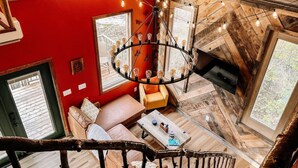 Un interior acogedor con pared roja, suelo de madera, lámpara circular y una escalera.
