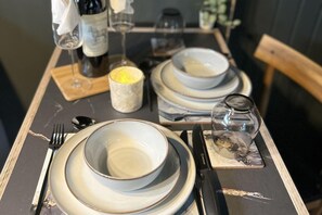 Una mesa servida con platos, cuencos, cubiertos y una vela.