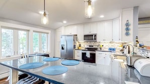 A modern kitchen with white cabinets, stainless steel appliances, and a central island with blue placemats. - Quiet Leonard Lake Retreat,  Beautiful Waterfront Home  (Ellsworth)