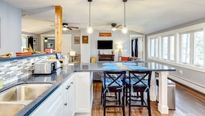 A modern kitchen with a central island, built-in appliances, and a dining area with bar stools. - Quiet Leonard Lake Retreat,  Beautiful Waterfront Home  (Ellsworth)
