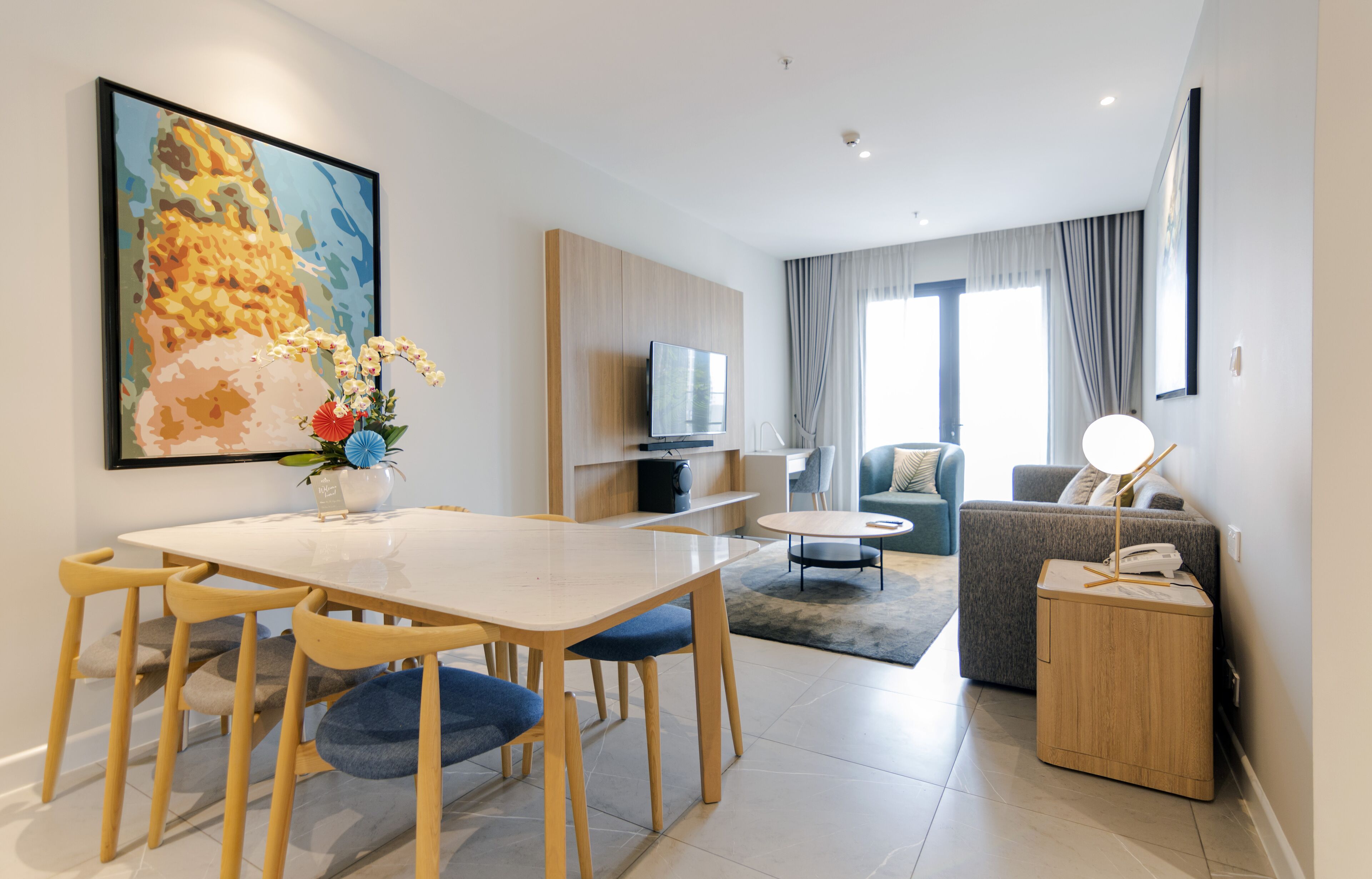 Ein modernes Wohnzimmer mit Essbereich, einer Couch, einem Fernseher und einer Lampe.