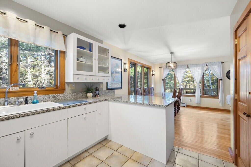 A kitchen with a large island, white cabinets, and a view of the outdoors.
