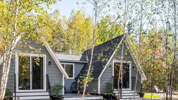 Une maison moderne avec un toit en pente, de grandes fenêtres et une véranda.