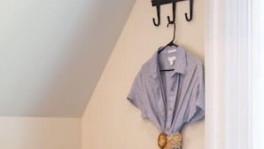 Un canapé gris agrémenté d’un coussin à motifs, un porte-manteau mural avec un peignoir, et une petite plante posée sur une table.