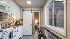 Une cuisine moderne avec des meubles blancs, une cuisinière et un coin repas comprenant une table et des chaises.