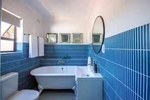 A bathroom with a bathtub, toilet, and sink. There are three framed mirrors on the wall. - Cape St. Blaize (Mossel Bay)