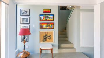 A hallway with a staircase, a red lamp, and a chair.