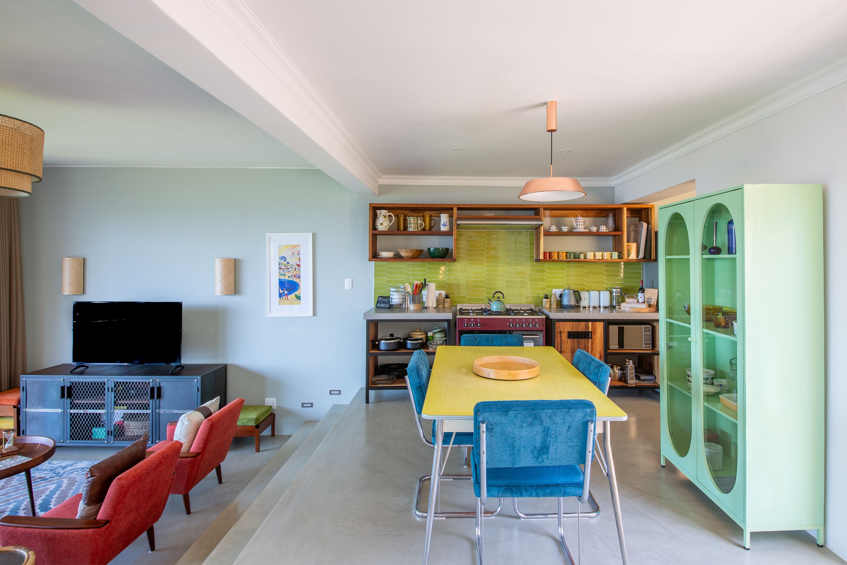Una sala de estar moderna con televisor, asientos y comedor.