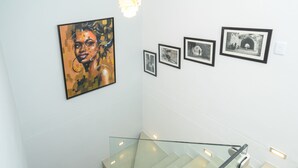 A staircase with glass railings and a wall with framed artwork.