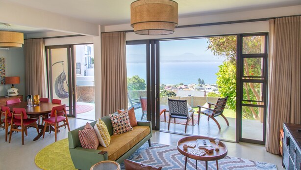 A spacious living area with a large sliding glass door leading to a balcony with a view of the sea.