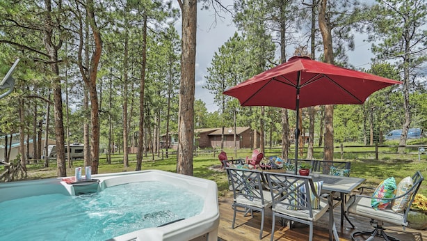 A hot tub on a wooden deck with a red umbrella, surrounded by trees. - Sunnywood (Woodland Park)
