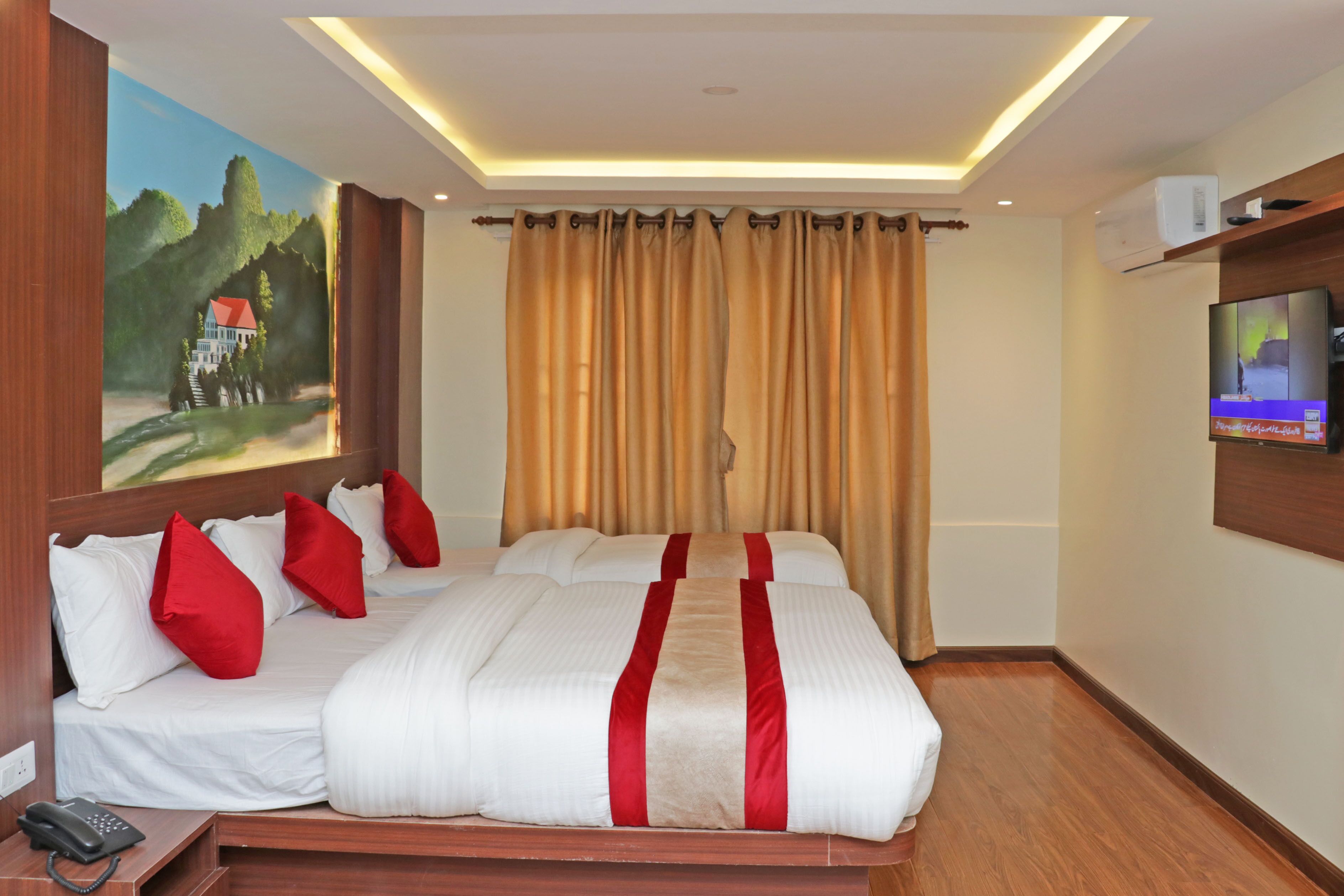 A hotel room with a large bed, a painting on the wall, a television, and a telephone on the side table.