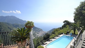 A pool with a view of the sea and mountains.