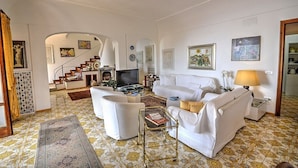 A spacious living room with a sofa set, a television, and a staircase leading to another level.