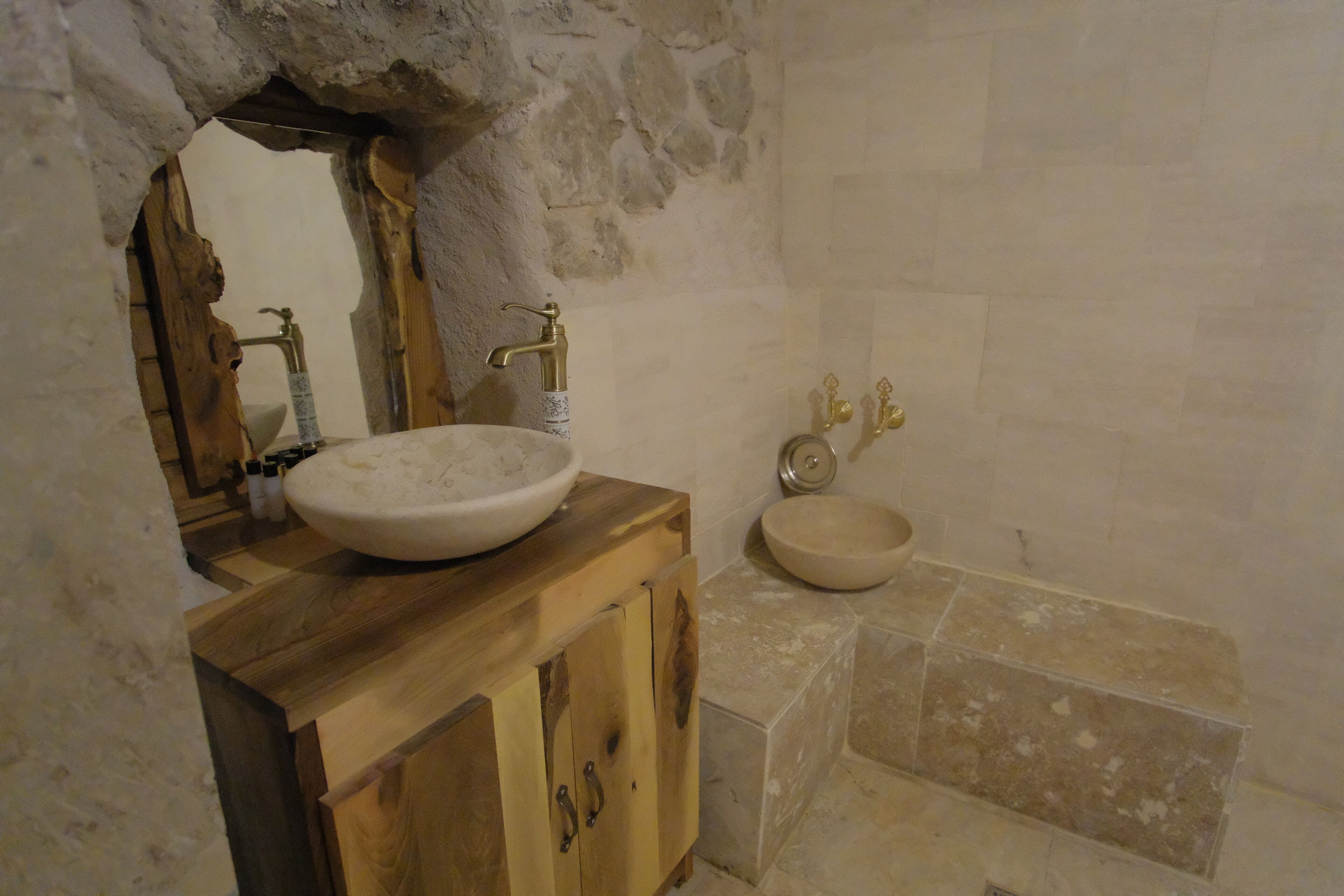 Un baño rústico con un tocador de madera, un lavabo blanco y un lavamanos aparte.