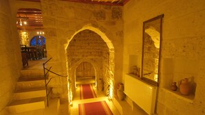 A stone staircase with a red carpet leading to a room with a large mirror and pottery on a shelf. - Euphoria Cave House (Nevsehir)